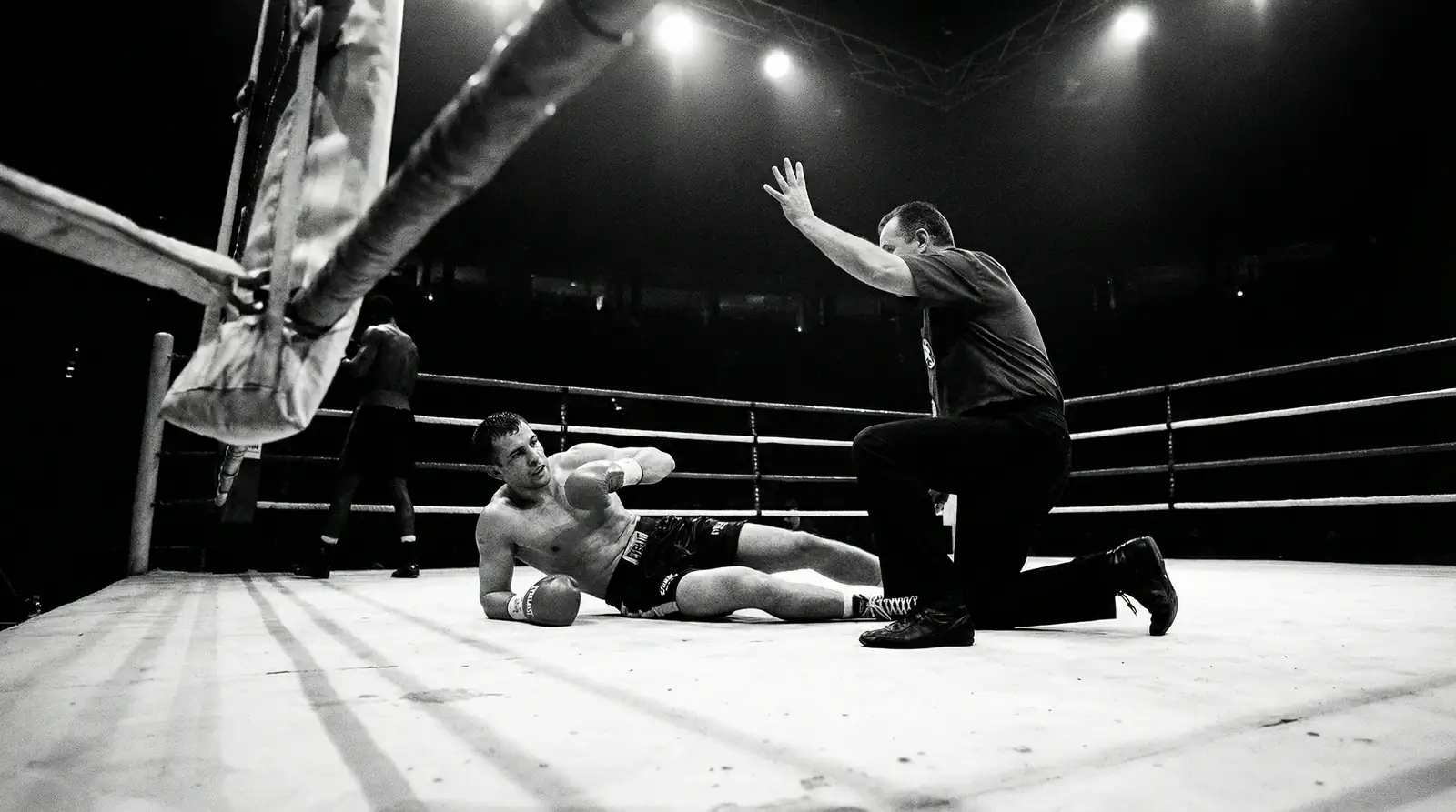 Ringrichter zählt einen am Boden liegenden Boxer im Boxring an